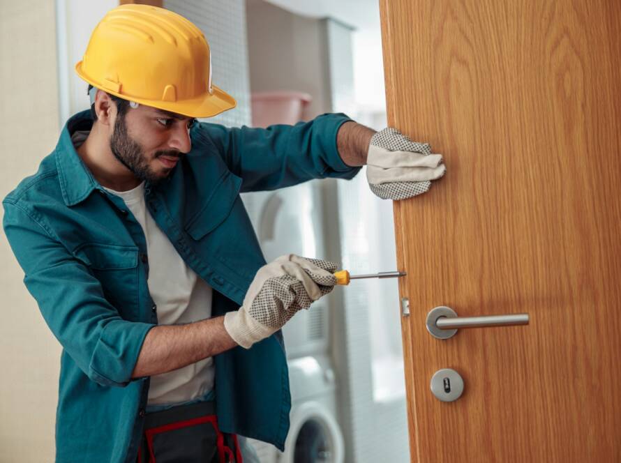 Locksmith workman in uniform installing door knob. Professional repair service